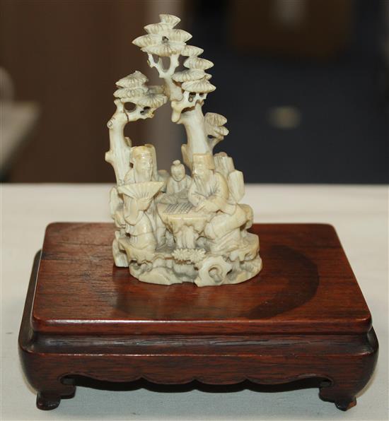 A Chinese ivory group of scholars playing weiqi beneath a pine tree, 19th century, 8.7cm, wood stand, slight repair